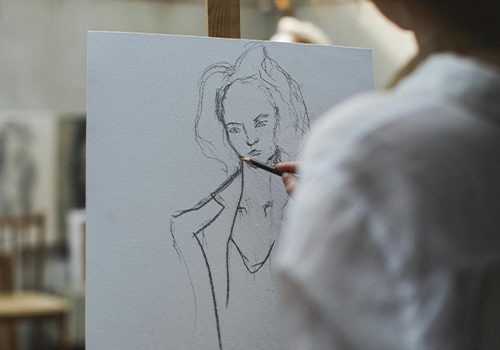 Un participant d’atelier d’art dessinant un paysage sous les conseils d’un animateur.