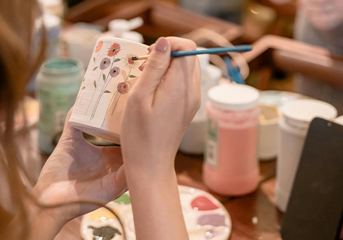 Une animatrice aidant une personne âgée à mélanger des couleurs sur sa palette.